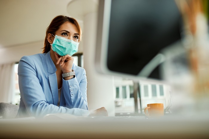 Low angle view of businesswoman with face mask working on desktop PC in the office.
