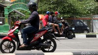 Tampak pengendara membonceng dua orang dan tidak mengenakan helm saat berkendara.