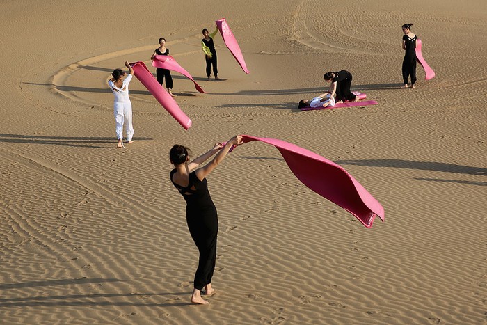 ORDOS, CHINA - JULY 20:  Dancers perform yoga on the dunes of Xiangshawan Desert, also called Sounding Sand Desert on July 20, in Ordos of Inner Mongolia Autonomous Region, China. Xiangshawan is China's famous tourist resort in the desert. It is located along the middle section of Kubuqi Desert on the south tip of Dalate League under Ordos City. Sliding down from the 110-metre-high, 45-degree sand hill, running a course of 200 metres, the sands produce the sound of automobile engines, a natural phenomenon that nobody can explain.  (Photo by Feng Li/Getty Images)