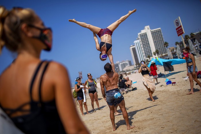 A man holds a sign showing Prime Minister Benjamin Netanyahu and his wife Sara during a protest against government's decision to close beaches during the three-week nationwide lockdown due to the coronavirus pandemic, in Tel Aviv, Israel, Saturday, Sept 19, 2020. Israel went back into a full lockdown on Friday to try to contain a coronavirus outbreak that has steadily worsened for months as its government has been plagued by indecision and infighting. Hebrew sighs reads 