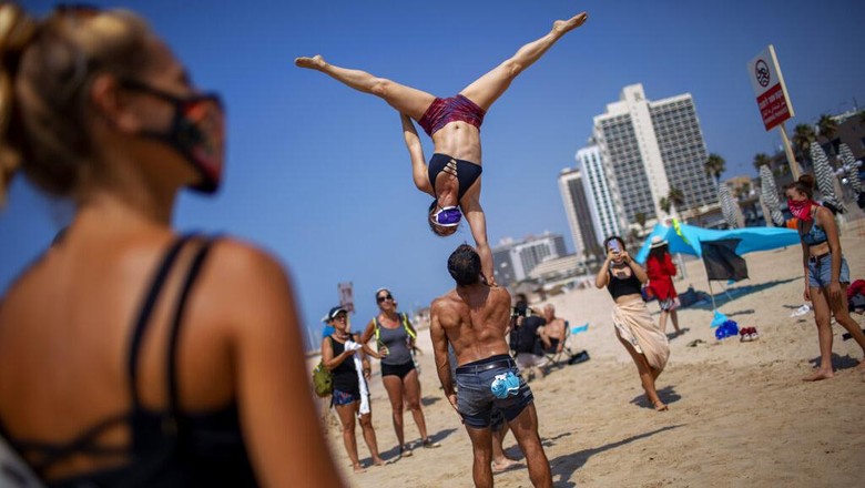 A man holds a sign showing Prime Minister Benjamin Netanyahu and his wife Sara during a protest against governments decision to close beaches during the three-week nationwide lockdown due to the coronavirus pandemic, in Tel Aviv, Israel, Saturday, Sept 19, 2020. Israel went back into a full lockdown on Friday to try to contain a coronavirus outbreak that has steadily worsened for months as its government has been plagued by indecision and infighting. Hebrew sighs reads 