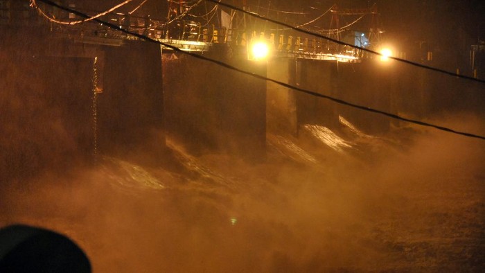 Pengendara motor melintas di atas jembatan sungai Warga memotret derasnya debit air sungai Ciliwung di Bendung Katulampa, Kota Bogor, Jawa Barat, Senin (21/9/2020).  Tingginya intensitas curah hujan di wilayah Puncak, Kabupaten Bogor menyebabkan ketinggian muka air di Bendung Katulampa mengalami peningkatan hingga mencapai 250 cm atau status Siaga 1 sehingga warga di bantaran Sungai Ciliwung diminta untuk waspada. ANTARA FOTO/Arif Firmansyah/pras.