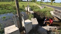 Kedua anak tersebut bahu-membahu mengumpulkan pasir di area persawahan tersebut.