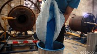 Seorang pekerja menyiapkan bahan baku untuk pembuatan tangki air.