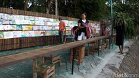 Lukisan milik anak-anak tersebut dipajang berderet di dinding bambu yang berada di tepi Sungai Oya, Siluk, Bantul, Yogyakarta.