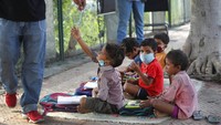 Veena membelikan buku, pensil, buku catatan, dan bahan belajar lainnya, untuk anak-anak belajar di bawah naungan pohon beringin yang rindang.  