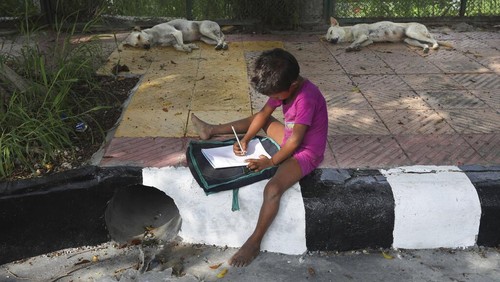 A boy learns addition on a sidewalk class taught by an Indian couple, Veena Gupta and her husband Virendra Gupta, in New Delhi, India, on Sept. 3, 2020. It all began when Veenas maid complained that with schools shut, children in her impoverished community were running amok and wasting time. The street-side classes have grown as dozens of children showed keen interest. Now the Guptas, with help from their driver, teach three different groups three times a week, morning and evening. As most schools in India remain shut since late March when the country imposed a nationwide lockdown to curb the spread of COVID-19, many switched to digital learning and taking classes online. (AP Photo/Manish Swarup)
