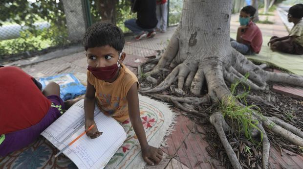Veena Gupta, right, performs stretch exercises during a class for underprivileged children she conducts with her husband Virendra Gupta, in New Delhi, India, on Sept. 3, 2020. It all began when Veena's maid complained that with schools shut, children in her impoverished community were running amok and wasting time. The street-side classes have grown as dozens of children showed keen interest. Now the Guptas, with help from their driver, teach three different groups three times a week, morning and evening. As most schools in India remain shut since late March when the country imposed a nationwide lockdown to curb the spread of COVID-19, many switched to digital learning and taking classes online. (AP Photo/Manish Swarup)