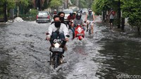 Pengendara melintasi genangan yang mulai surut di akses masuk ke Perumahan Green Garden, Kedoya, Jakarta, Selasa (22/9/2020).