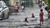 Anak-anak bermain di genangan air.