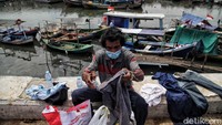 Seorang warga mengumpulkan pakaian di kawasan Kalibaru, Cilincing, Jakarta.