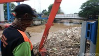Tampak alat berat sedang mengangkat sampah yang berada di Pintu Air Manggarai, Jakarta.