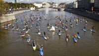 Orang-orang mengarahkan papan SUP mereka di sepanjang Selat Sungai Moskow selama Festival Selancar SUP (Stand Up Paddle) di Moskow, Rusia.  