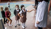 Siswa kelas satu mengenakan masker pelindung berbaris untuk diambil suhu tubuhnya sebelum memasuki gedung sekolah di Florya Ugur College di Istanbul, Turki, Senin (21/9/2020) waktu setempat.  