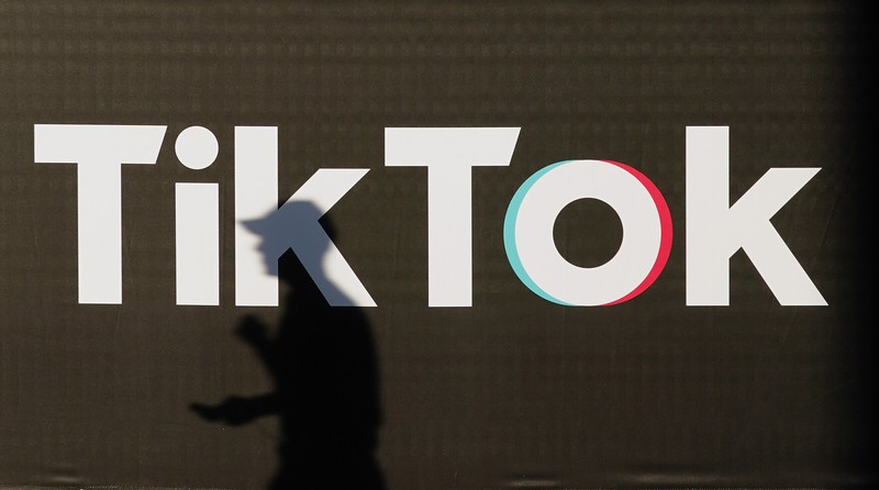 BERLIN, GERMANY - SEPTEMBER 21: A young man holding a smartphone casts a shadow as he walks past an advertisement for social media company TikTok on September 21, 2020 in Berlin, Germany. U.S. President Donald Trump has given preliminary approval for Oracle, Walmart and other investors to take over TikTok and create a new U.S.-based company called TikTok Global. (Photo by Sean Gallup/Getty Images)