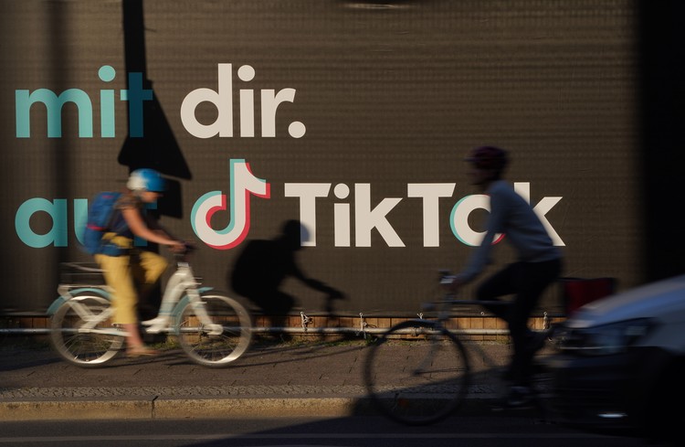 BERLIN, GERMANY - SEPTEMBER 21: A young man holding a smartphone casts a shadow as he walks past an advertisement for social media company TikTok on September 21, 2020 in Berlin, Germany. U.S. President Donald Trump has given preliminary approval for Oracle, Walmart and other investors to take over TikTok and create a new U.S.-based company called TikTok Global. (Photo by Sean Gallup/Getty Images)