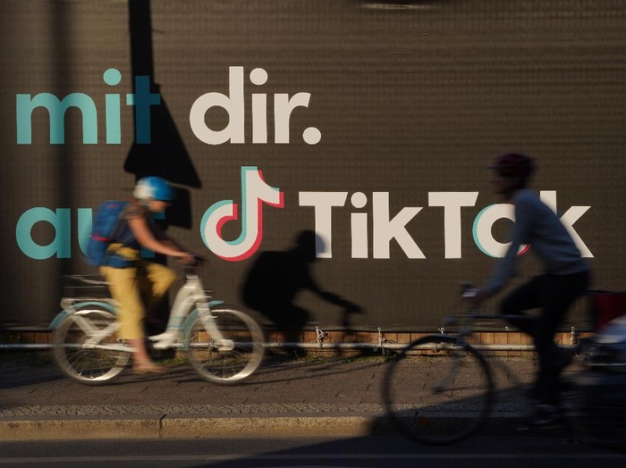 BERLIN, GERMANY - SEPTEMBER 21: A young man holding a smartphone casts a shadow as he walks past an advertisement for social media company TikTok on September 21, 2020 in Berlin, Germany. U.S. President Donald Trump has given preliminary approval for Oracle, Walmart and other investors to take over TikTok and create a new U.S.-based company called TikTok Global. (Photo by Sean Gallup/Getty Images)