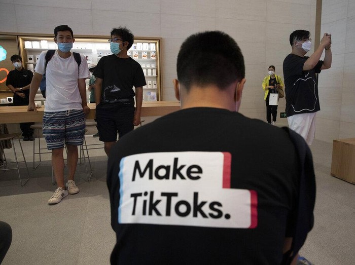 FILE - In this July 17, 2020, file photo, a man wearing a shirt promoting TikTok is seen at an Apple store in Beijing, China. TikTok’s parent company ByteDance has chosen Oracle over Microsoft as a new American technology partner to help keep the popular video-sharing app operating in the U.S., according to a person familiar with the deal.(AP Photo/Ng Han Guan, File)