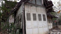 Selain itu, tampak dinding luar rumah yang terbuat dari kayu, namun kondisinya ada yang jebol. Rumah tersebut berada di tengah lahan yang ditanami pohon jati.