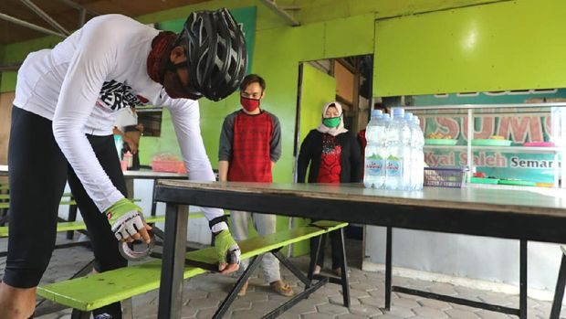 Ganjar ketika memasang lakban jaga jarak di warung pecel di Semarang