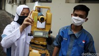 Siswa jurusan Geomatika melakukan pengukuran menggunakan theodolit.