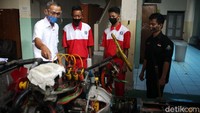 Para siswa mempelajari jeroan mobil dengan bimbingan guru.