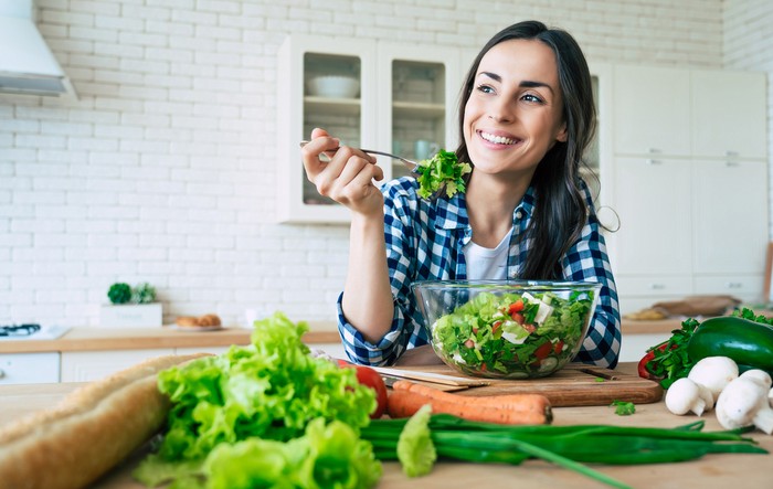 Diet makan salad Healthy lifestyle. Good life. Organic food. Vegetables. Close up portrait of happy cute beautiful young woman while she try tasty vegan salad in the kitchen at home.