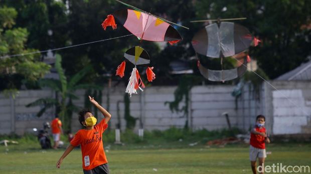 Sejumlah anak bermain layang-layang di kawasan Jakarta Barat. Anak-anak itu tampak mengenakan masker saat bermain layang-layang di lapangan terbuka.