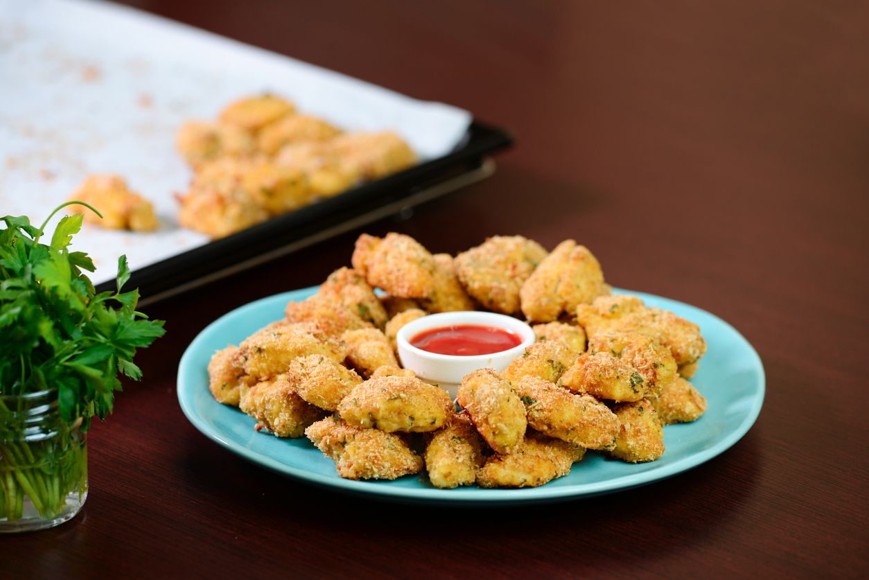 Fried crispy chicken nuggets with ketchup on the plate.