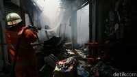 Petugas damkar terus menyemprot sumber api agar tidak merembet ke bangunan sekitar pasar.