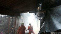 Petugas damkar menyusuri lorong-lorong pasar sambil menyemprotkan air agar api tidak membesar.