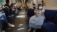 Tampak sejumlah wisatawan mengenakan masker saat menaiki kereta yang menuju ke Disneyland Hong Kong.