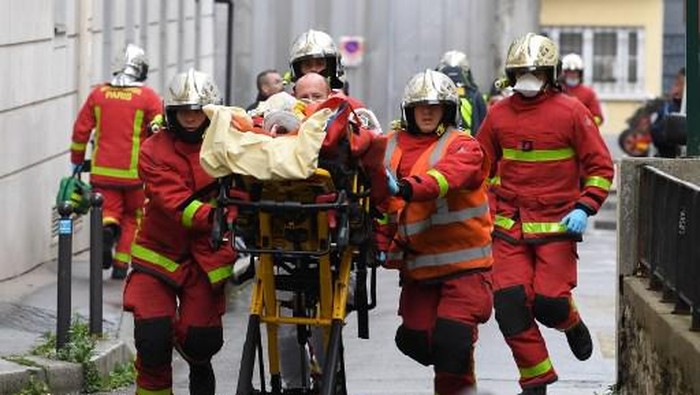 Petugas pemadam kebakaran Paris membawa korban penusukan di dekat eks kantor majalah Charlie Hebdo. (Photo by Alain JOCARD / AFP)