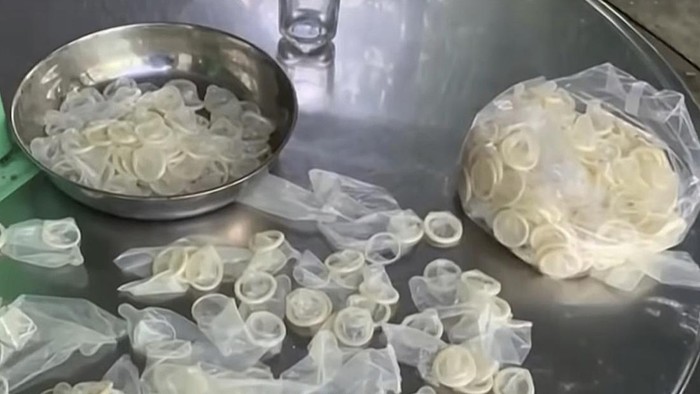 In this image from a video report by VTV, allegedly used condoms are being are being packed for sale in Binh Duong province, Vietnam on Sept. 10, 2020. Vietnamese police say they will investigate a factory that was found recycling about 320,000 used condoms for resale. (VTV via AP)