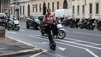 Seorang warga tampak mengendarai skuter listrik saat melintasi salah satu jalan yang berada di kawasan Milan, Italia.