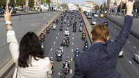Penonton menyapa pengendara sepeda motor selama parade. AP Photo/Alexander Zemlianichenko.