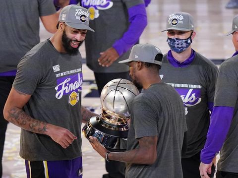 Los Angeles Lakers' Anthony Davis, left, looks at their trophy after beating the Denver Nuggets in an NBA conference final playoff basketball game Saturday, Sept. 26, 2020, in Lake Buena Vista, Fla. The Lakers won 117-107 to win the series 4-1. (AP Photo/Mark J. Terrill)