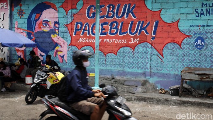 Mural Lawan Wabah COVID-19 Warga melintas di depan mural bertemakan lawan wabah Covid-19 di Pasar Serangan, Yogyakarta, Senin (28/09/2020). Gambar mural tersebut mengingatkan warga untuk melawan wabah Covid-19 dengan menerapkan 3M protokol kesehatan Covid-19 yaitu dengan mencuci tangan, menggunakan masker dan menjaga jarak fisik.