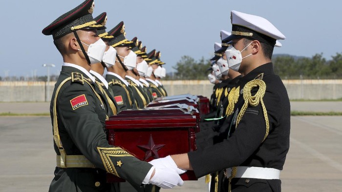 In this photo provided by the South Korea Defense Ministry, Chinese honor guard members, left, receive caskets containing the remains of Chinese soldiers from South Korean honor guards during the handing over ceremony at the Incheon International Airport in Incheon, South Korea, Sunday, Sept. 27, 2020. The remains of 117 Chinese soldiers who died in the 1950-53 Korean War were returned to China on Sunday in an annual repatriation delayed this year by the coronavirus outbreak. (South Korea Defense Ministry via AP)