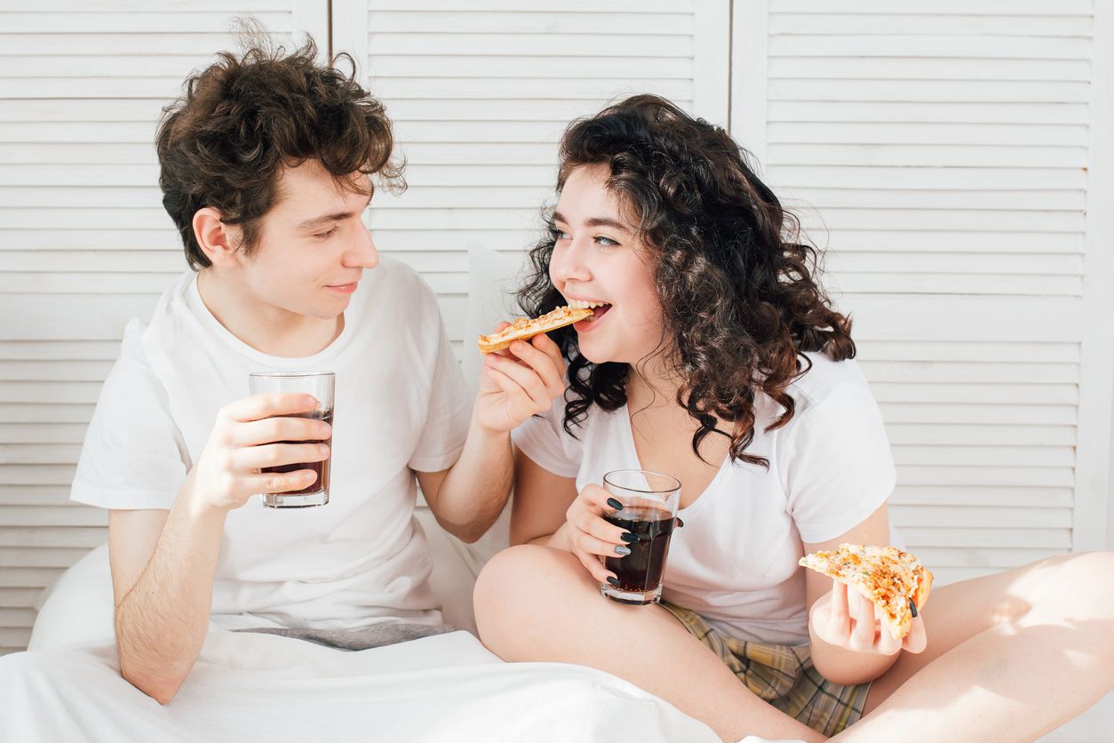 Loving couple watching TV in bed and eating pizza. The concept of love and romance. Toning.