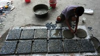 Seorang pekerja tengah membuat batu koral sikat di Jalan Kalimalang Raya, Jatibening, Kota Bekasi, Selasa (29/09/2020).