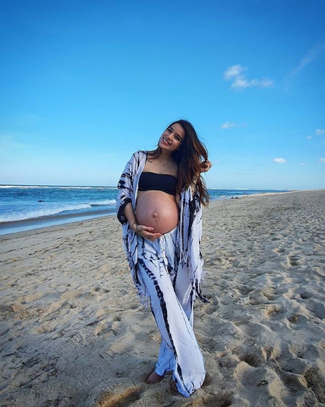 Mengenakan kemben dan setelan cardigan, Sheila Marcia tampak menebar senyum di tepi pantai. Maternity shoot ini digarap sendiri oleh sang suami, Dimas Akira. Foto: Instagram/@itssheilamj