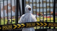 Dengan berdiri tegap, polisi ber-APD itu berjaga tepat di gerbang gedung DPR.