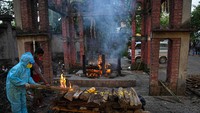 Seorang wanita melakukan ritual di dekat tubuh suaminya yang dikremasi akibat meninggal karena COVID-19 di Gauhati, India  