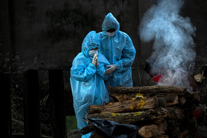 A nine year old boy, left, in personal protective equipment performs rituals during the cremation of his father who died of COVID-19 in Gauhati, India, Monday, Sept. 28, 2020. India’s confirmed coronavirus tally has reached 6 million cases, keeping the country second to the United States in number of reported cases since the pandemic began. (AP Photo/Anupam Nath)