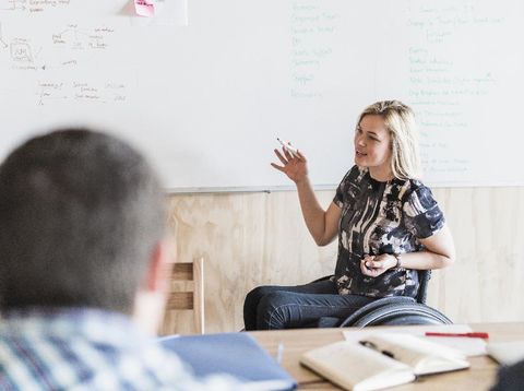 cacat fisik A photo of disabled businesswoman giving presentation. Smiling female is sitting on wheelchair. They are in creative office.