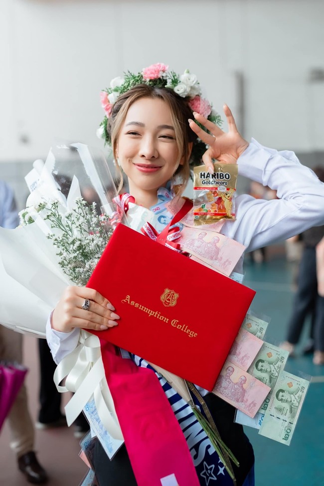 Peerada Namwong lulus SMA pada Agustus tahun ini. Meskipun memakai celana panjang dan dasi, dia tetap tampil feminin dengan makeup tipis, rambut disanggul dan karangan bunga sebagai penghias kepala. Foto: Facebook Peerada Namwong