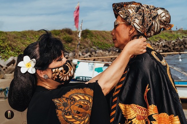 Tampak perempuan yang suka bergaya urakan itu beraksi dalam balutan atasan hitam yang dipadu dengan rok batik megar nan dramatis di atas perahu nelayan. Ia juga memaksimalkan gayanya dengan kacamata hitam. (Foto: Dok. Anne Avantie)