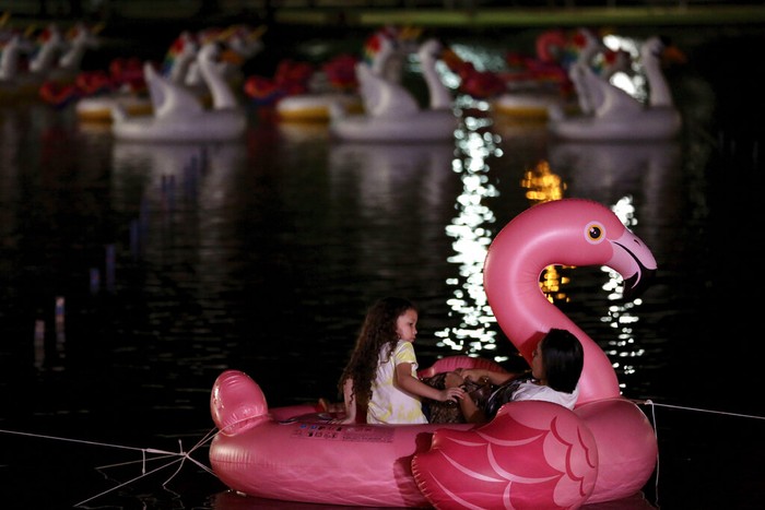 Serunya Festival Terapung Pertama di Brasil Attendants place a couple of inflatable flamingos on Sarah Kubstichek Lake as those onboard watch a movie during the first Floating Festival in Brasilia, Brazil, Wednesday, Sept. 30, 2020. The festival is the first in Brazil were people sit in inflatable boats and pedal boats, anchored in fixed spots and watch a movie, like an aquatic version of a drive-in cinema. (AP Photo/Eraldo Peres)