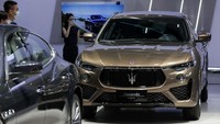 Seorang SPG dengan memakai masker berdiri di samping mobil Maserati.